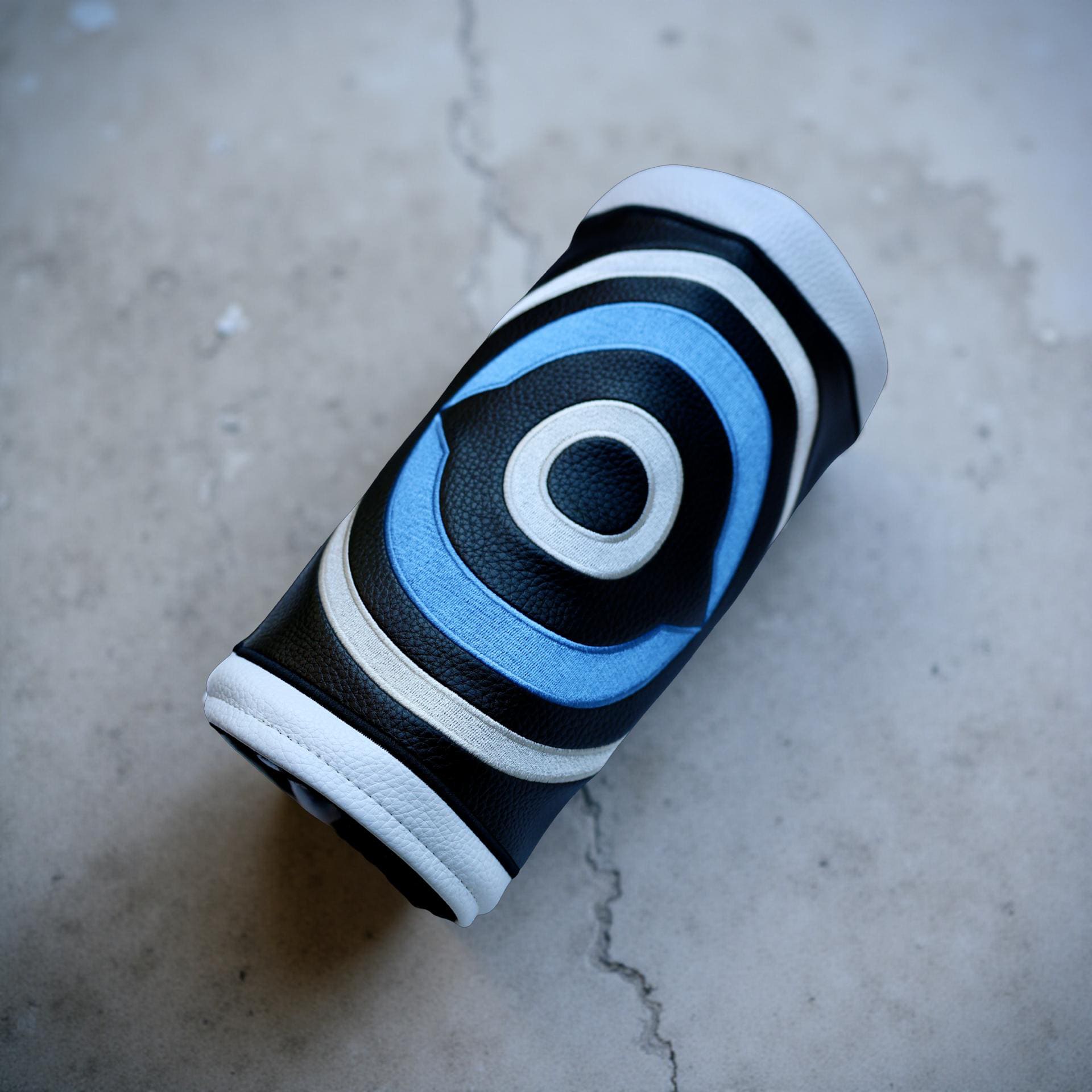 Fore Eye driver headcover on a concrete surface capturing modern minimal golf aesthetic.