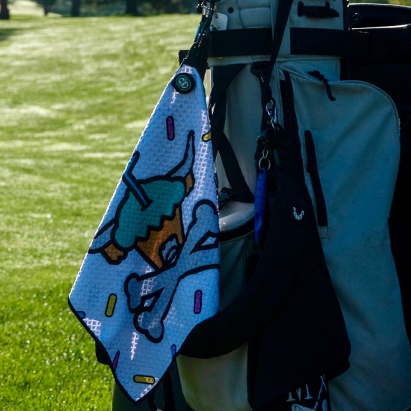 Johnny Cupcakes x Caddy Collective Culture golf towel with Looper cupcake skull and sprinkle design hanging on a golf bag