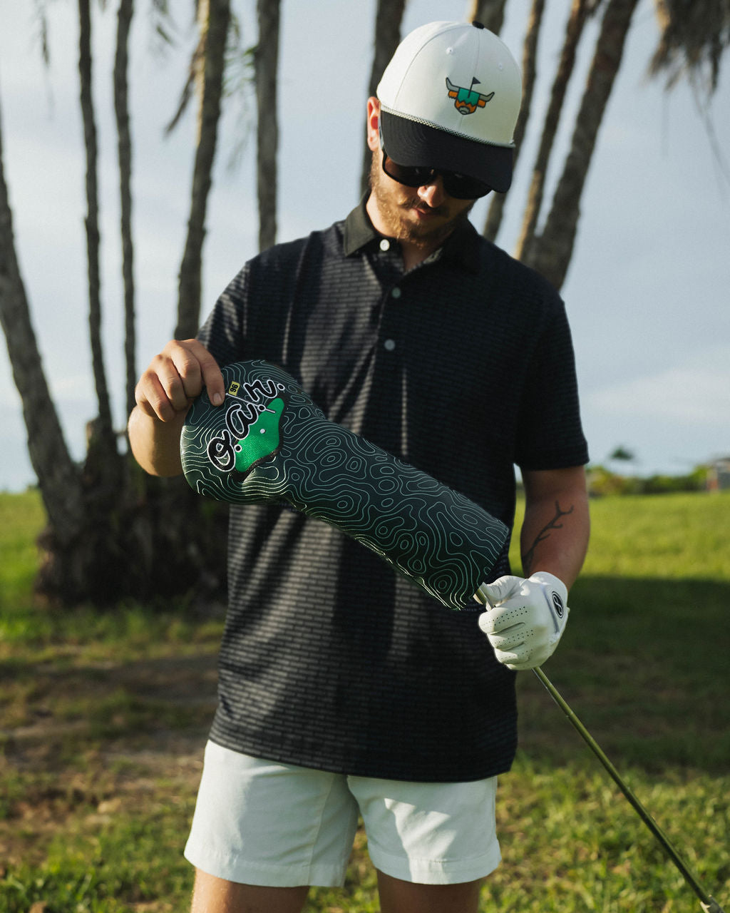 Man holding a golf club with a brand logo on a golf course