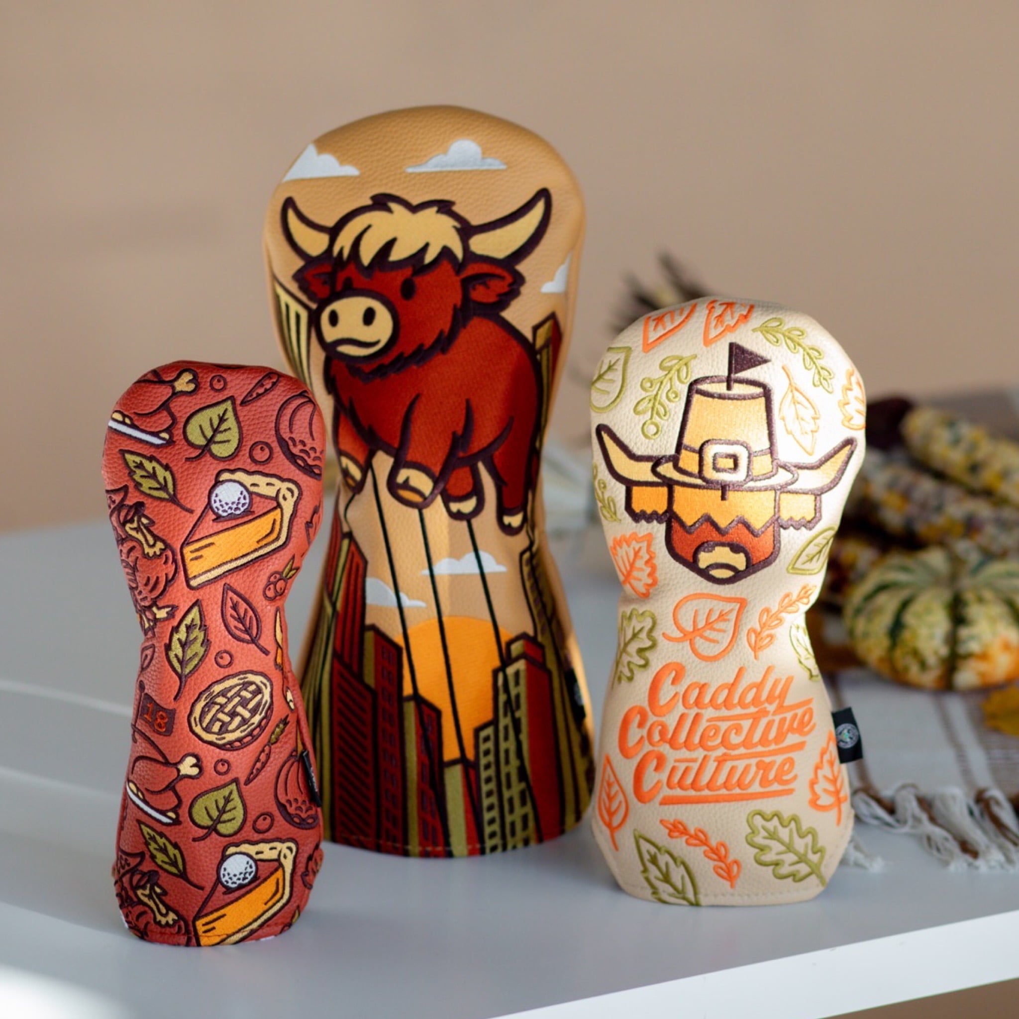 Harvest Parade driver headcover photographed with Pilgrim Looper and Autumn Feast headcovers in a seasonal setting.
