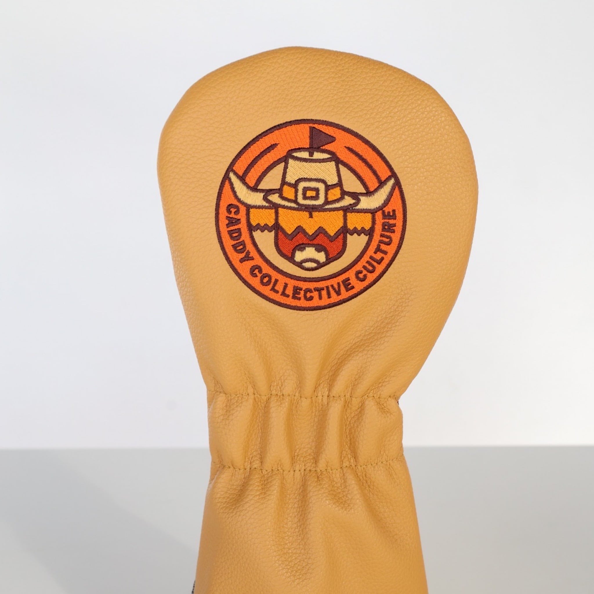 Back of the Harvest Parade driver headcover featuring the Pilgrim Looper logo on mustard leather.