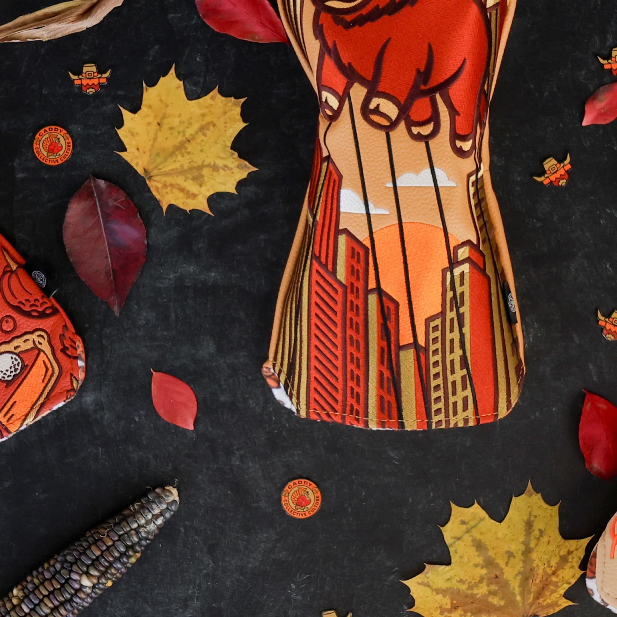 Harvest Turkey ball marker by Caddy Collective Culture shown in a fall-themed flat-lay with leaves, corn, and seasonal golf headcovers.