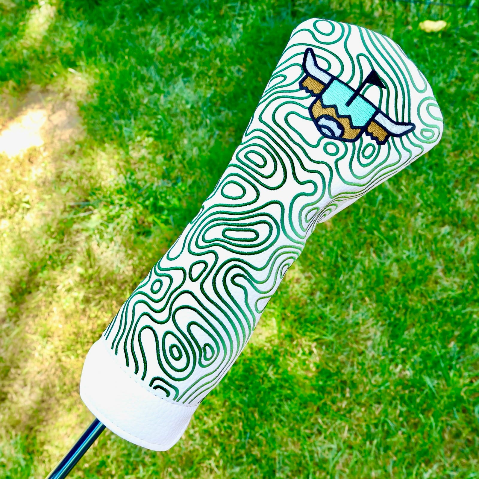 Hybrid white headcover with Looper logo on golf course grass background