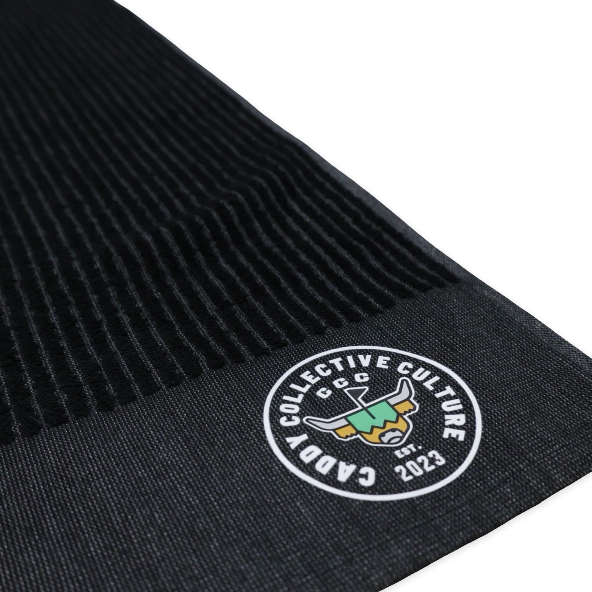 Close-up of printed Caddy Collective Culture logo on black golf towel