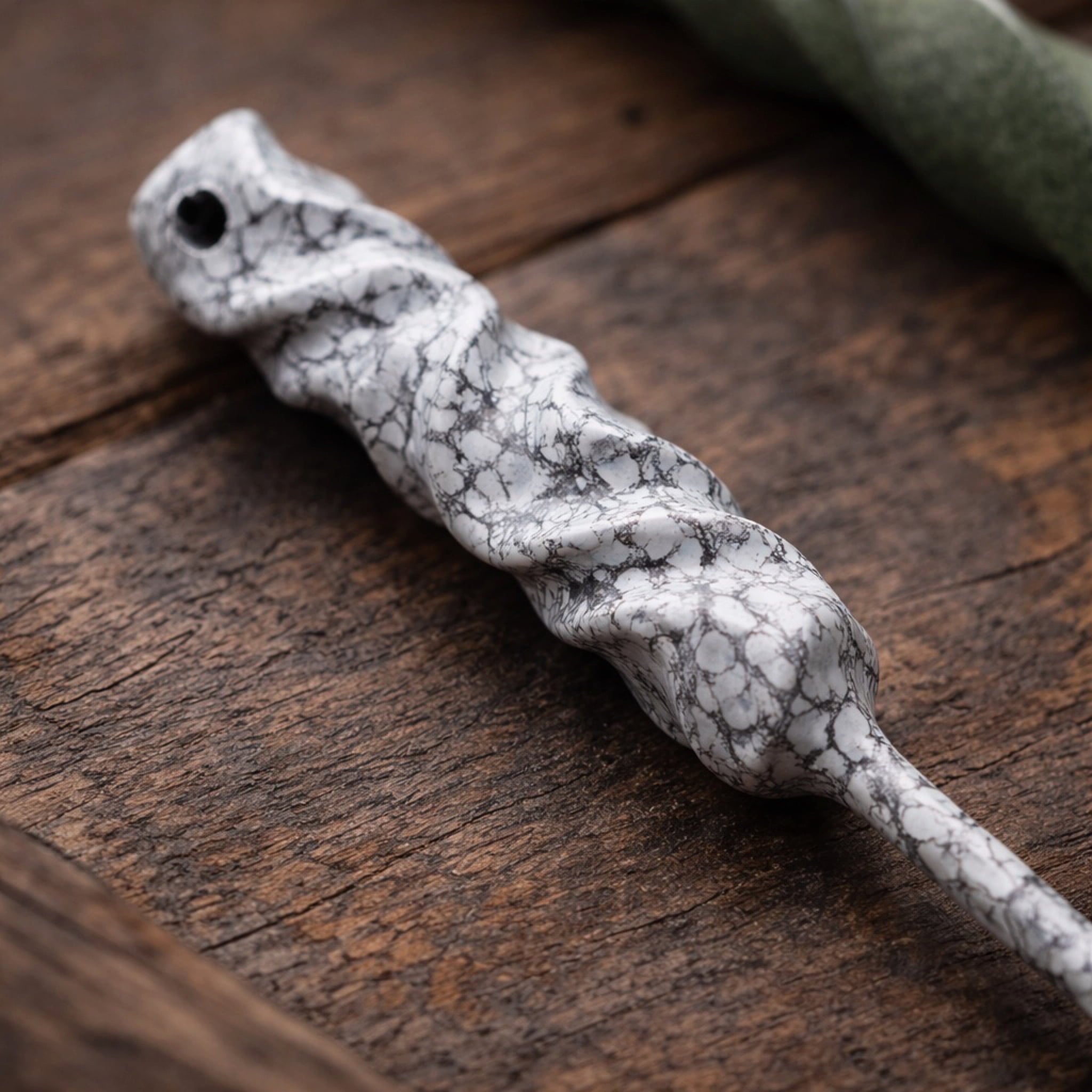 Close-up of the Dual-Twist divot tool in white finish from the Twisted Metal collection, resting on a dark wood surface.