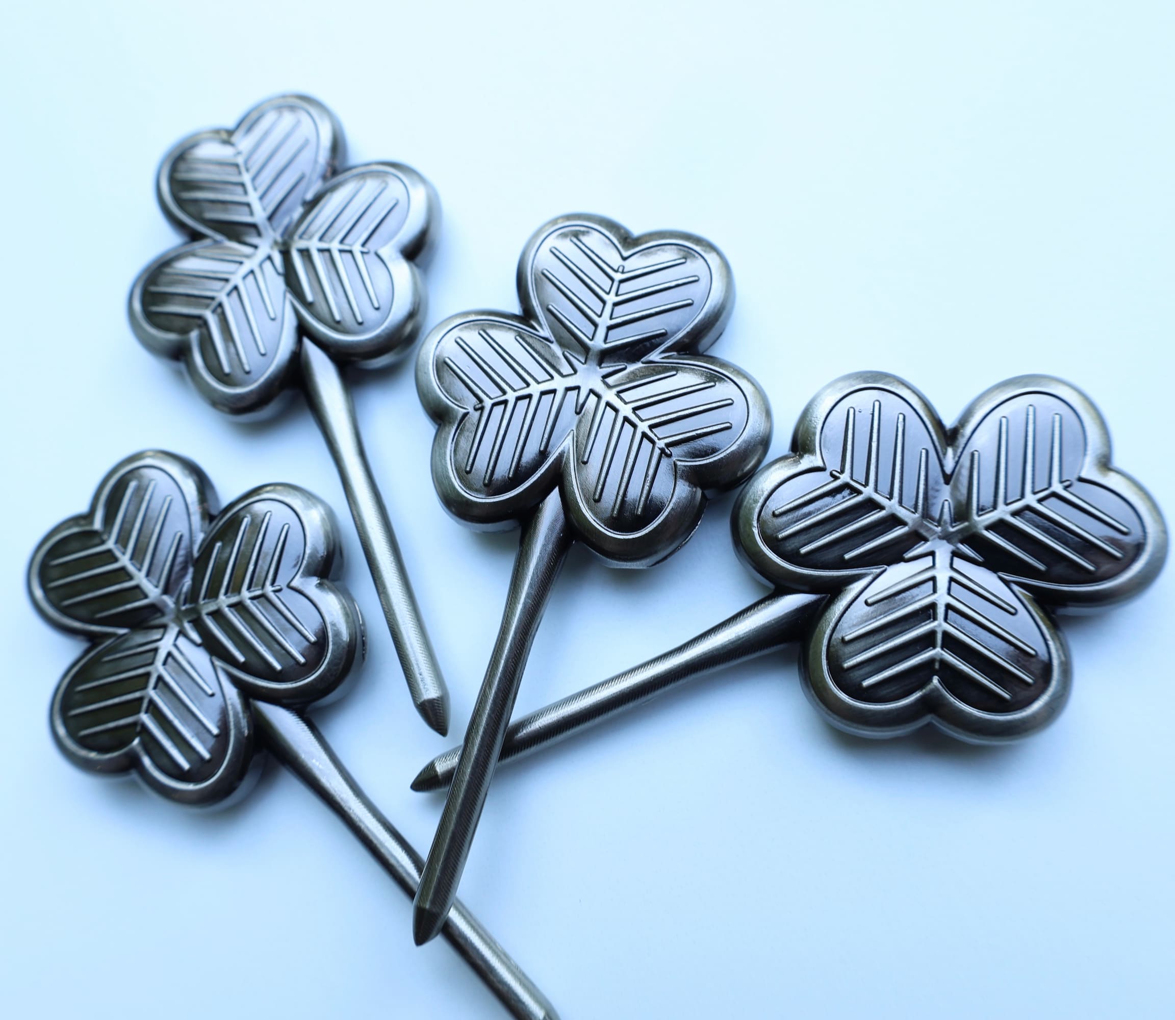 Collection of four clover-shaped golf divot tools photographed on light background