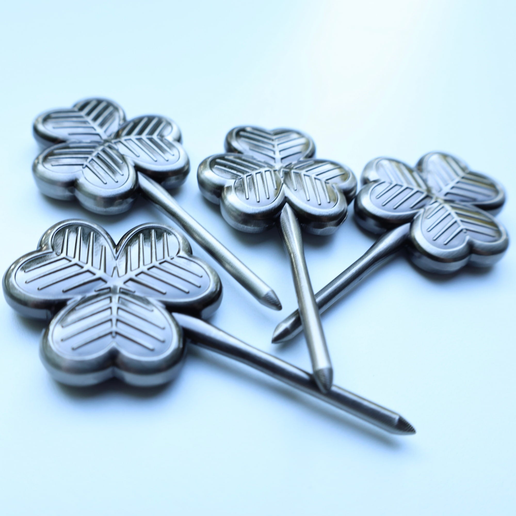 Four CCC clover divot tools displayed diagonally showing texture and shine