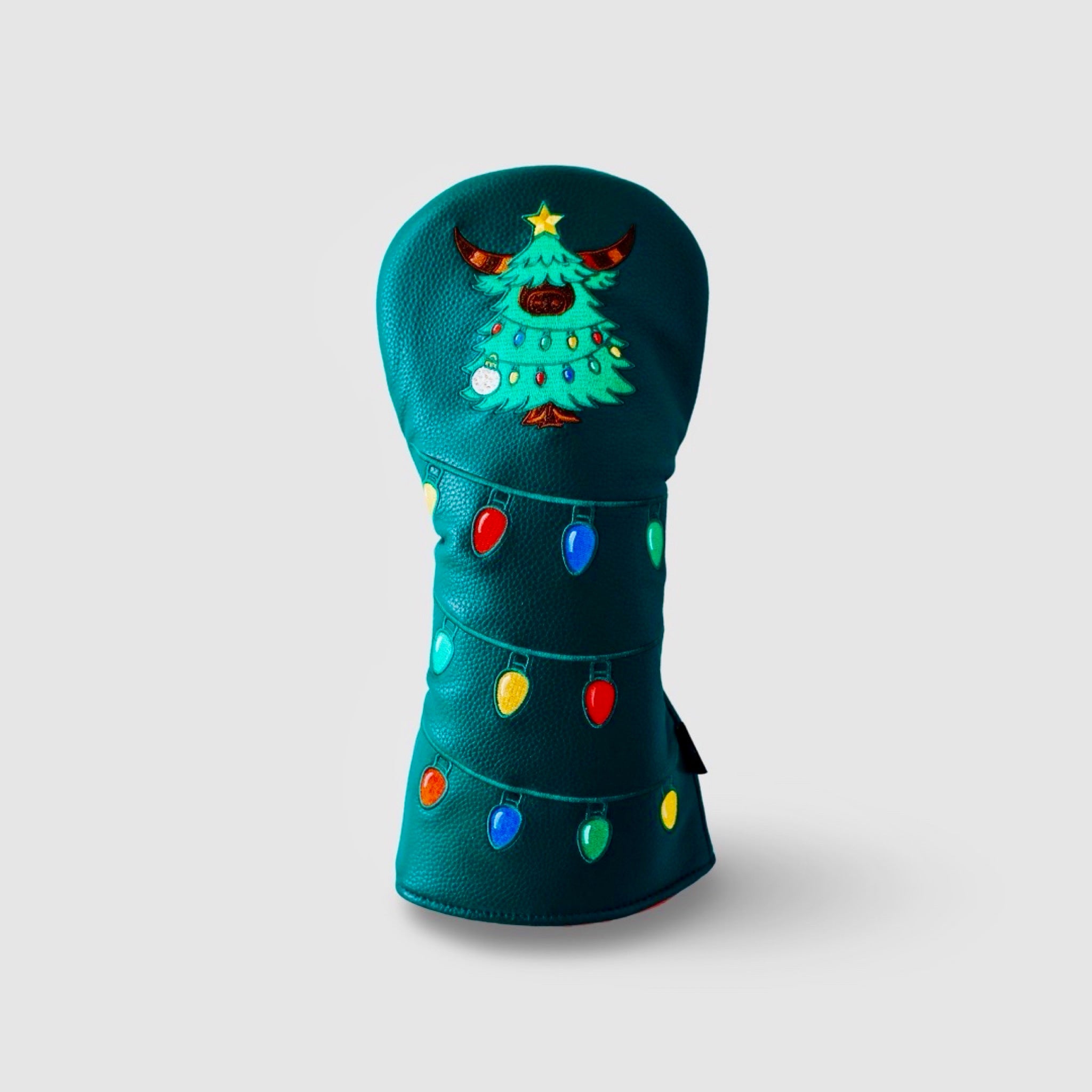 Studio image of the Evergreen driver headcover on a clean gray background, showing embroidered lights and Looper Christmas tree.