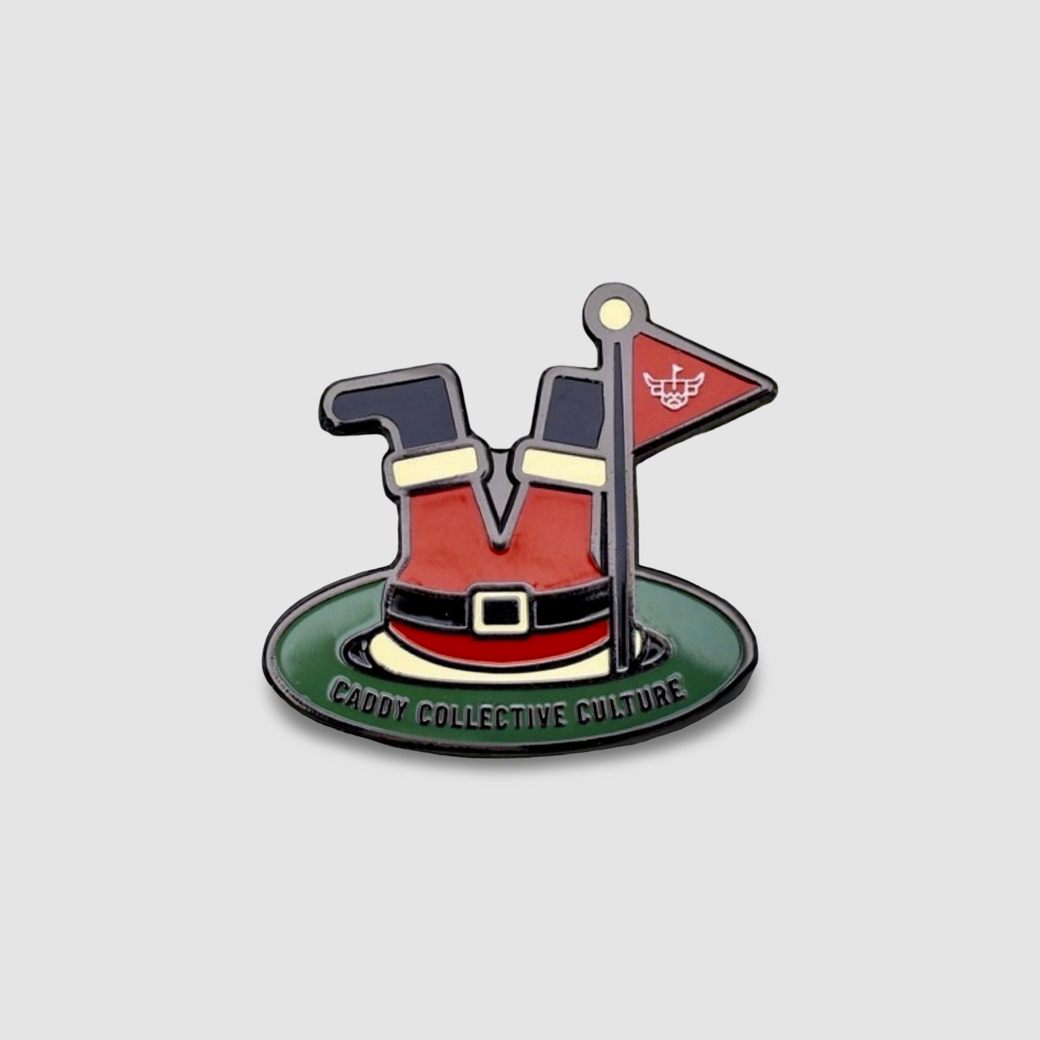 Studio image of the Santa’s Soft Landing golf ball marker featuring Santa’s legs in a golf hole with a flag and Caddy Collective Culture detailing.