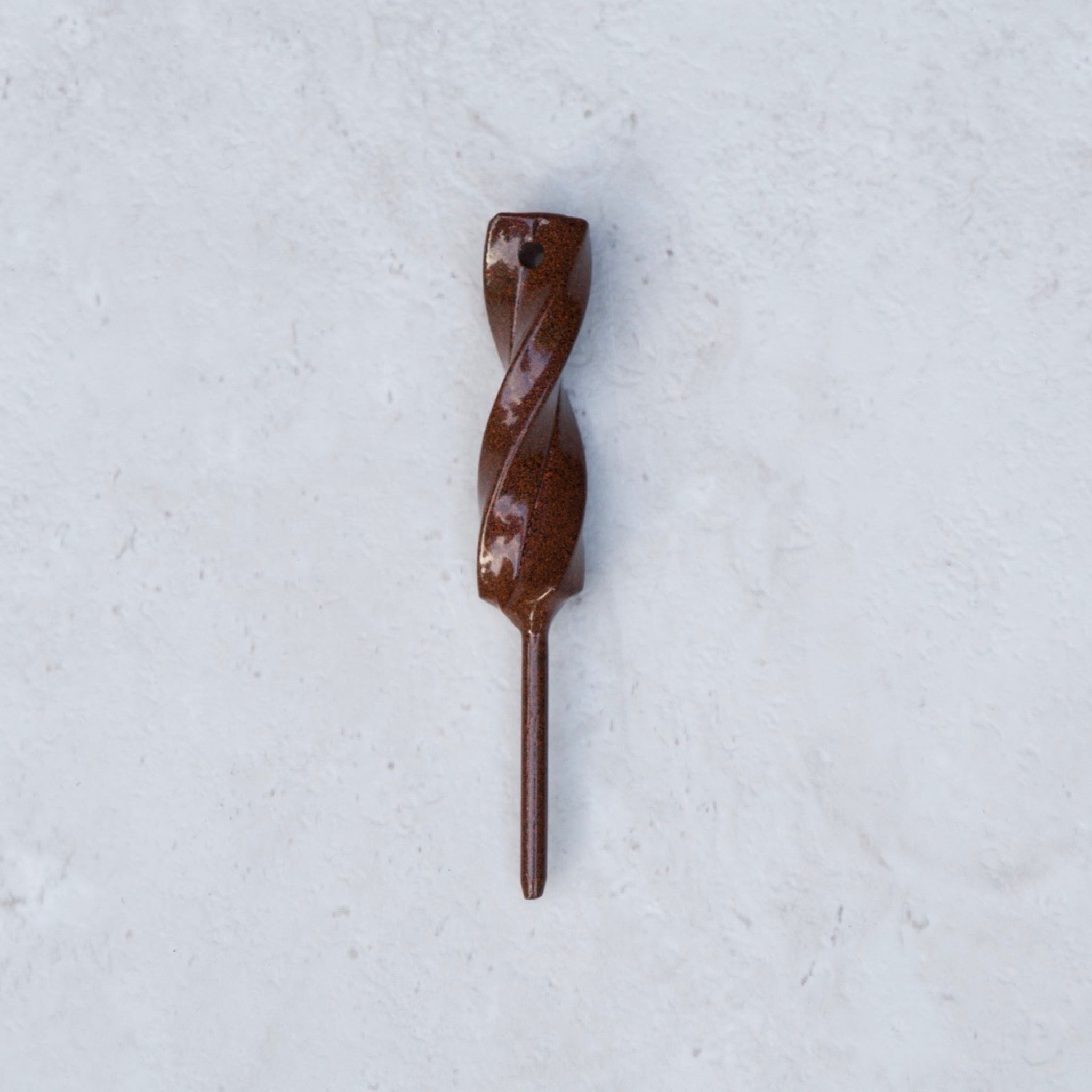 Rustic Hand Forged Twisted Divot Tool photographed on a textured stone background, showcasing the handcrafted twisted steel design.