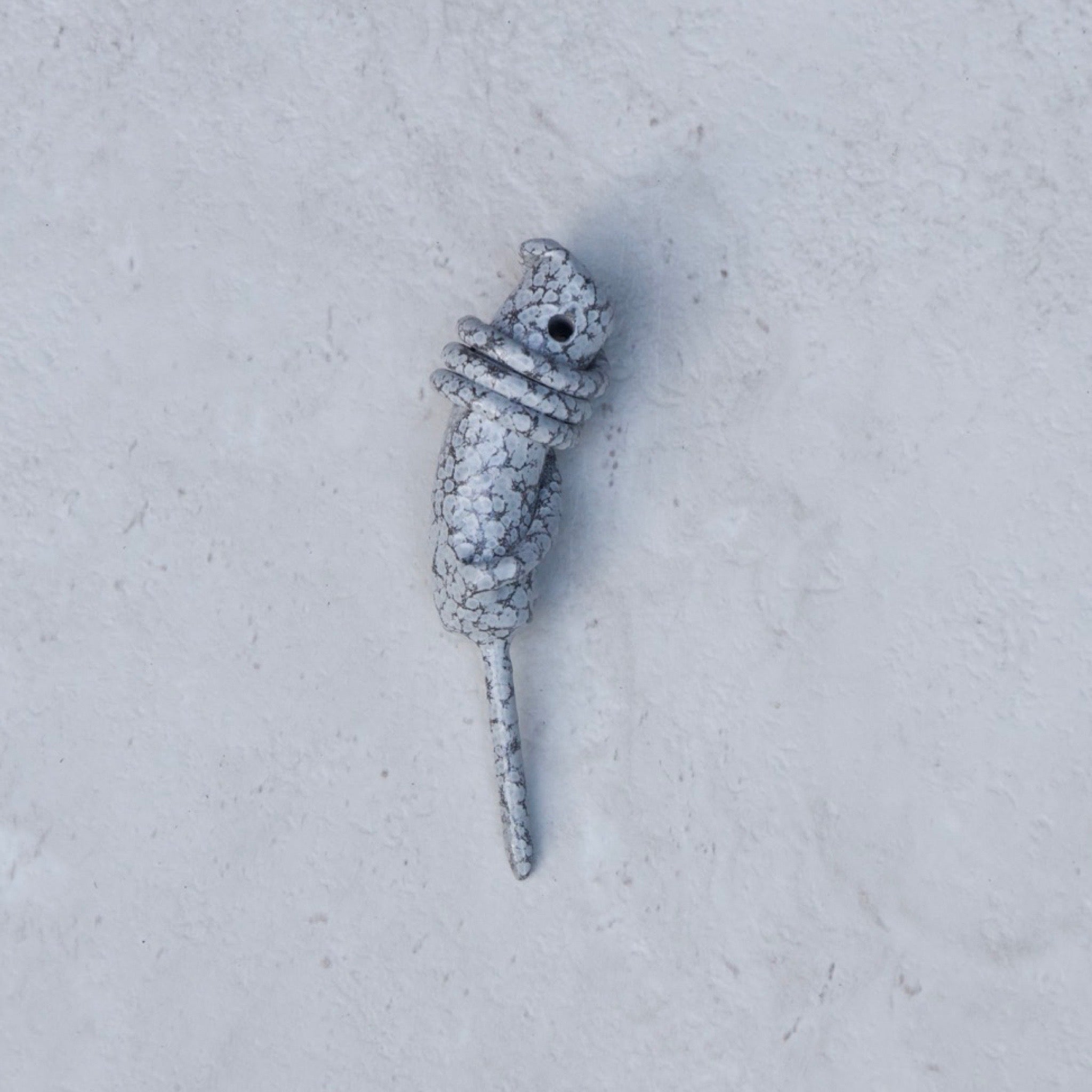 Stone White Hand Forged Wrapped Divot Tool showcasing the sculptural wrapped steel design on a textured stone background.