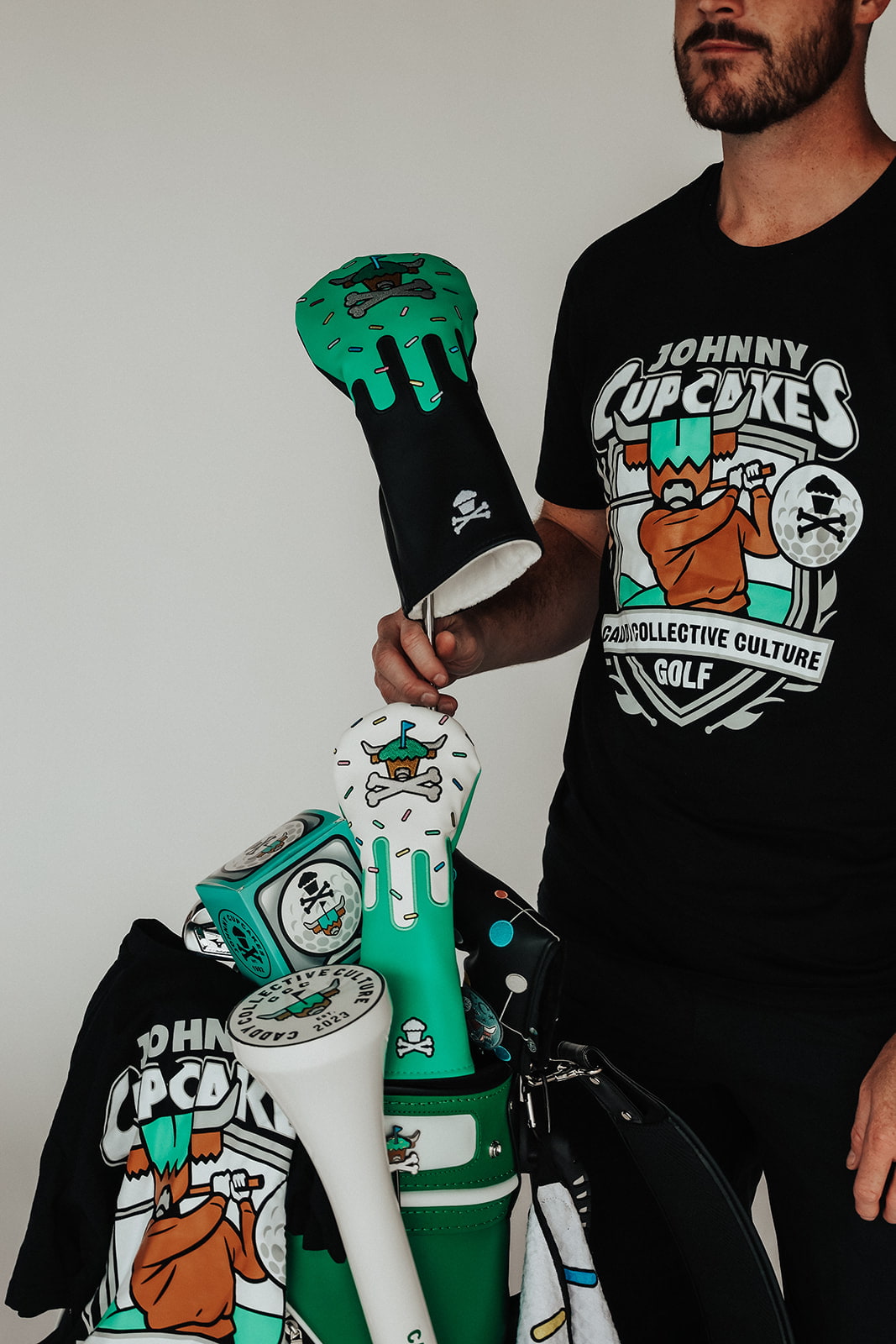 Johnny Cupcakes x Caddy Collective Culture golf collection full set including headcovers, divot tool, ball marker, towel, and t-shirt displayed in golf bag.