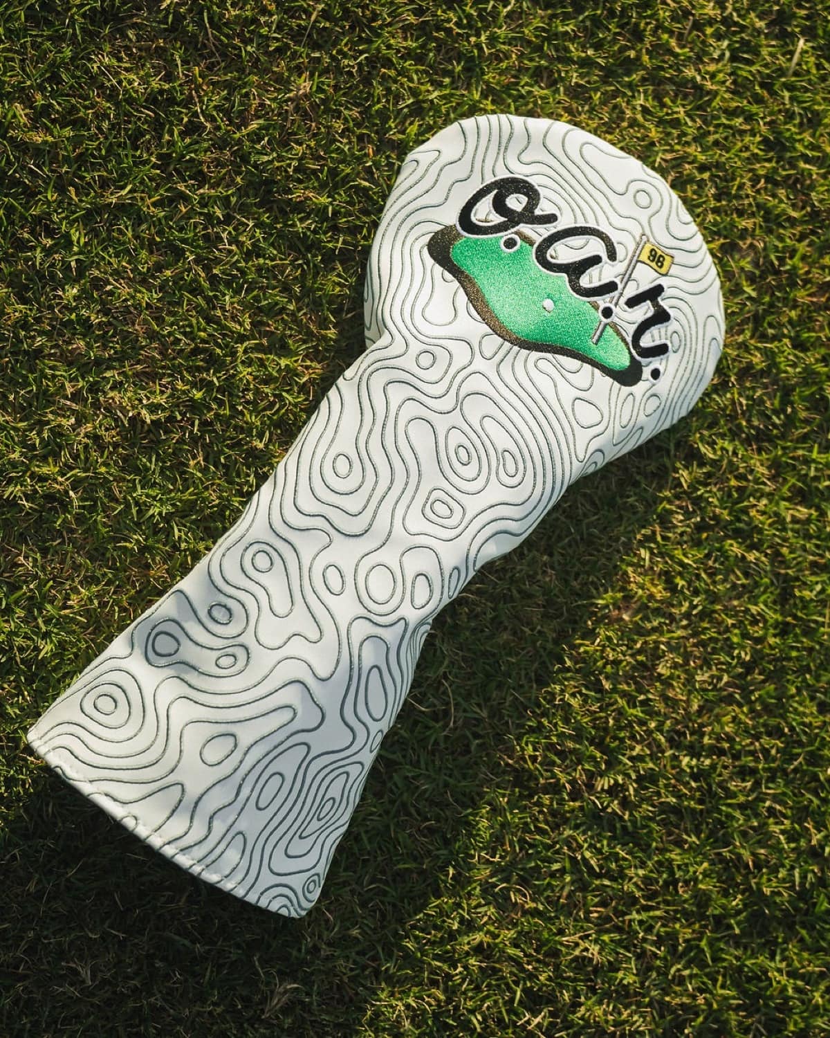 White custom O.A.R. golf headcover designed by Caddy Collective Culture on a golf course.
