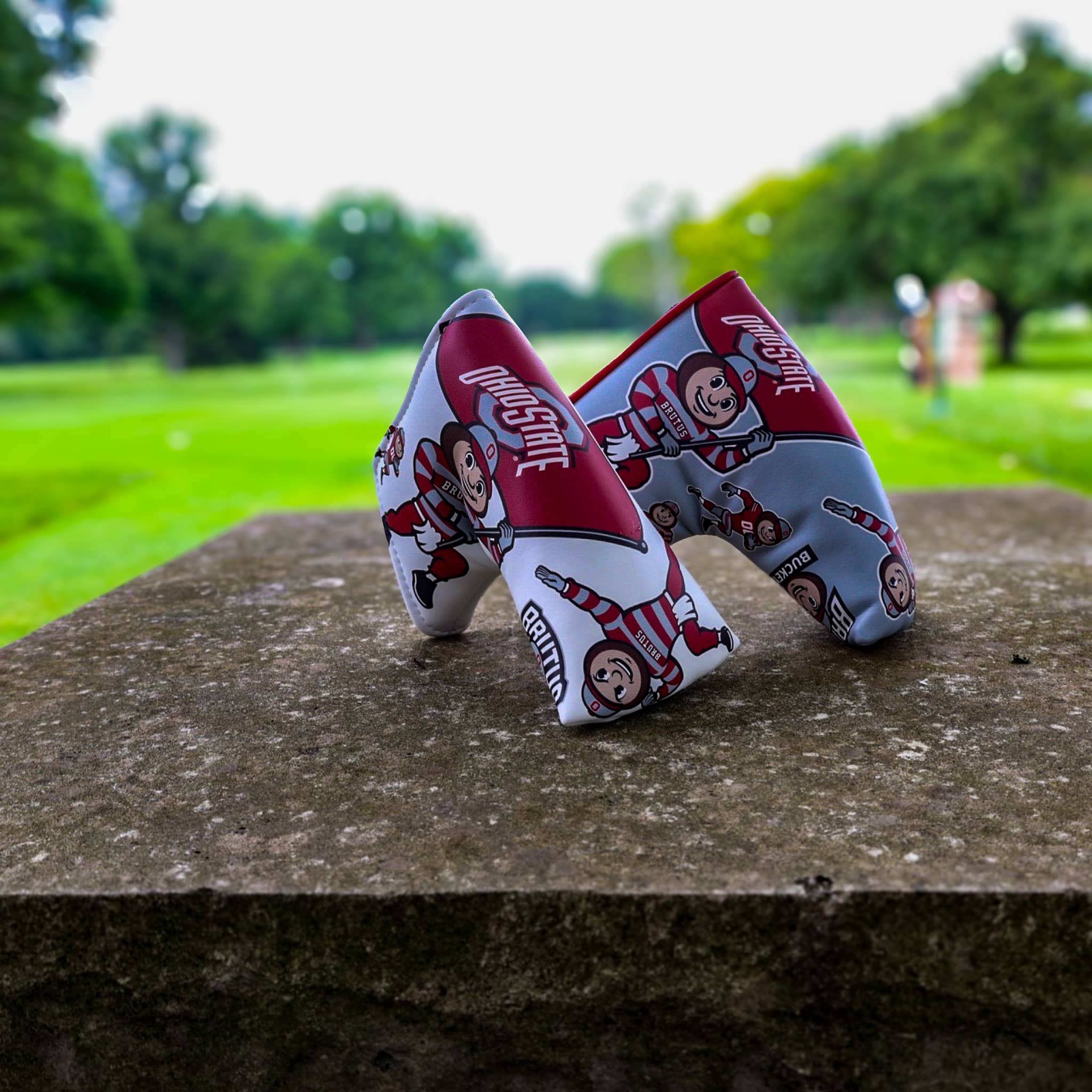 Pair of Ohio State Brutus blade putter headcovers displayed on a golf course featuring officially licensed Buckeyes artwork.