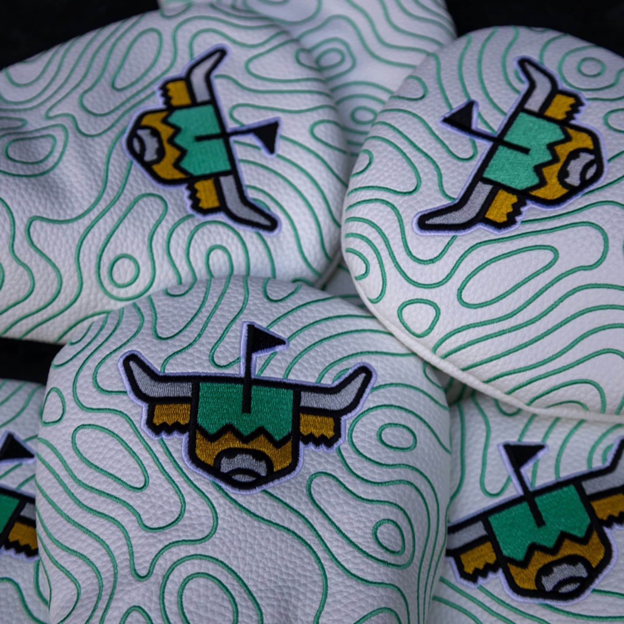 Terrain Driver Headcover on a golf bag showing the white pebbled grain leather and embroidered green contour pattern.