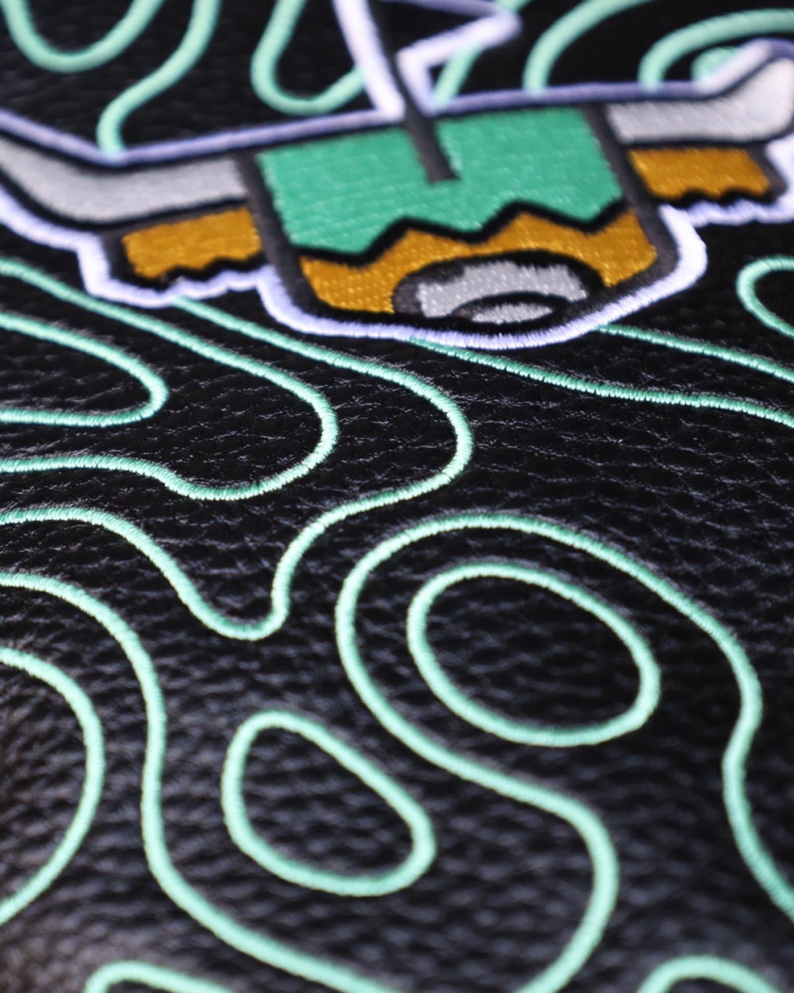 Close-up of the Terrain Driver Headcover – Midnight highlighting the embroidered green topographic pattern on black pebbled leather.