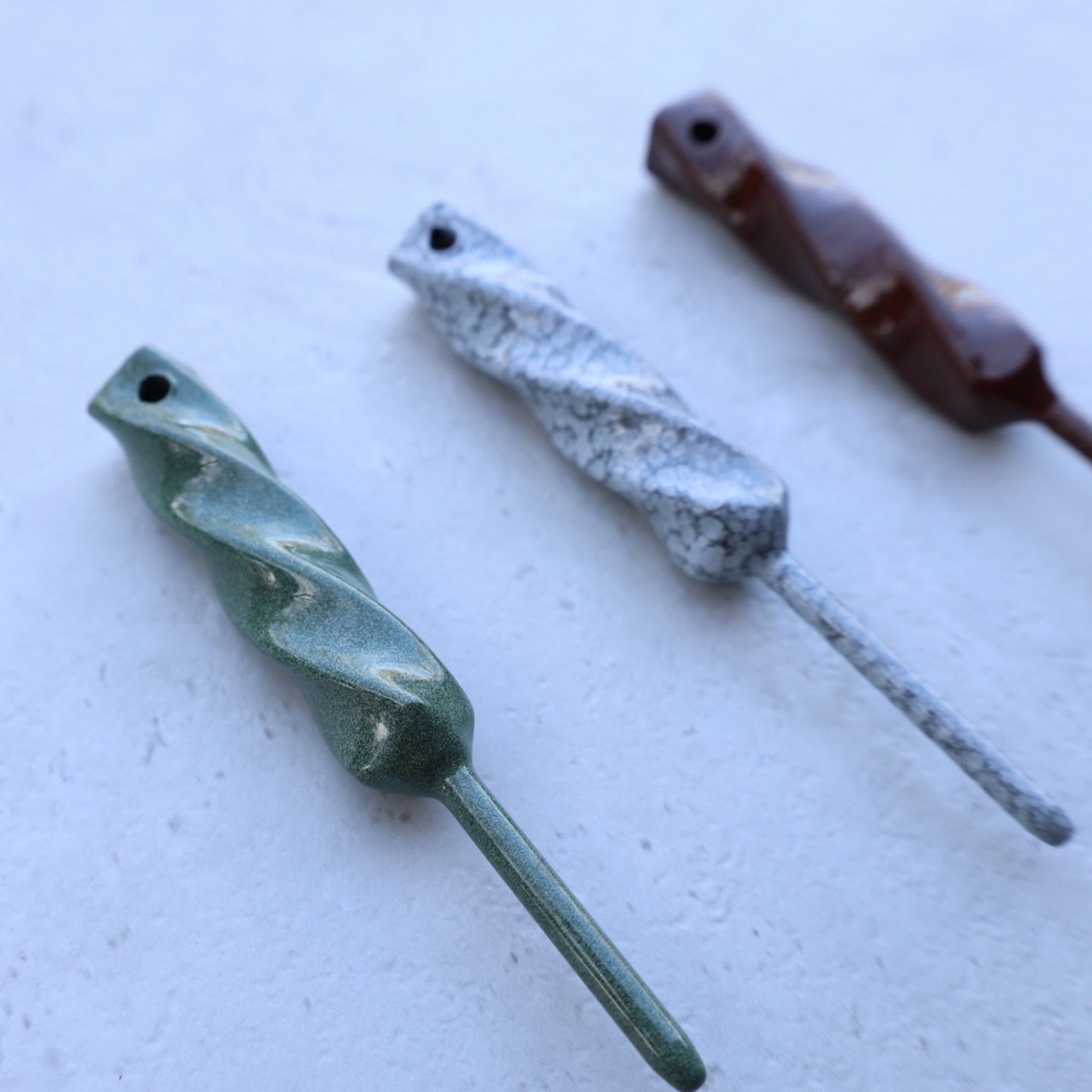 Lifestyle photo of Twisted Metal single prong divot tools arranged on light textured background showcasing finish variations