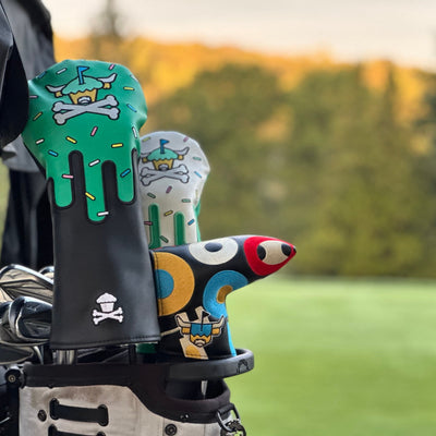 Johnny Cupcakes x Caddy Collective Culture golf headcovers on a bag: green sprinkle drip driver cover, white matching fairway cover, and black blade putter cover with Looper in colorful pop-art sunglasses
