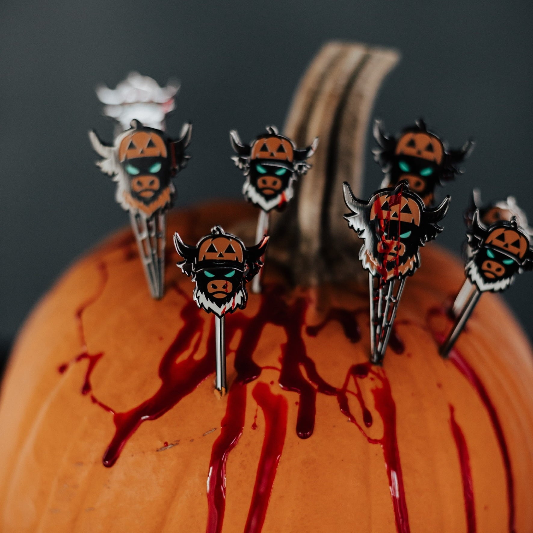 Caddy Collective Culture Looper After Dark Halloween divot tools featuring jack-o’-lantern Looper designs arranged on a pumpkin with red accents in a dark moody setting.