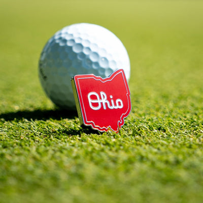 Script Ohio Ball Marker resting next to golf ball