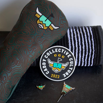 Angled view of Looper’s Field Kit including embroidered green driver headcover, striped golf towel, logo practice disc and divot tool.