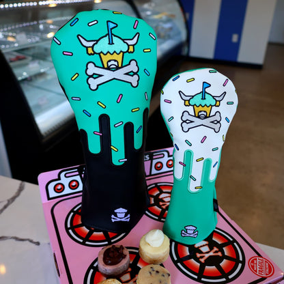 Johnny Cupcakes x Caddy Collective Culture golf driver and fairway headcovers with sprinkle design, displayed in bakery setting on pink oven box with cupcakes.
