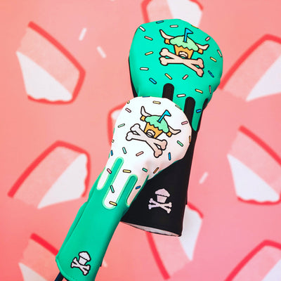Johnny Cupcakes x Caddy Collective Culture golf headcovers with sprinkle cupcake design, close-up against pink cheesecake wall background.