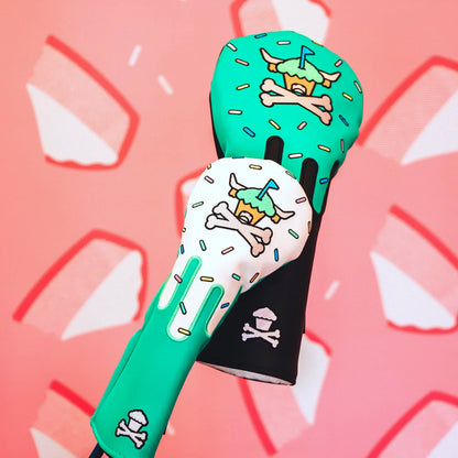 Johnny Cupcakes x Caddy Collective Culture golf headcovers with sprinkle cupcake design, close-up against pink cheesecake wall background.