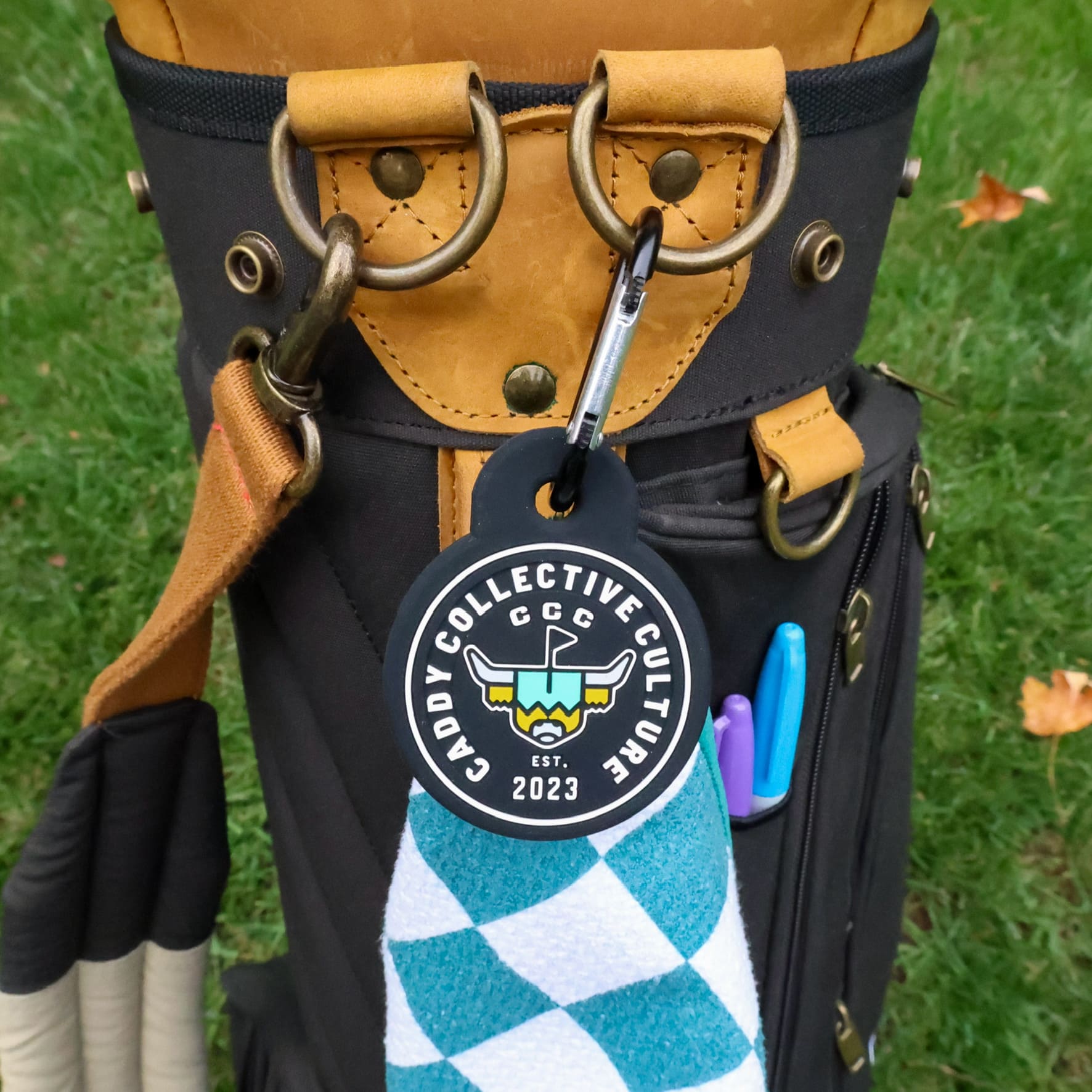 The Link magnetic towel attachment holding a golf towel on a golf bag with Caddy Collective Culture branding.