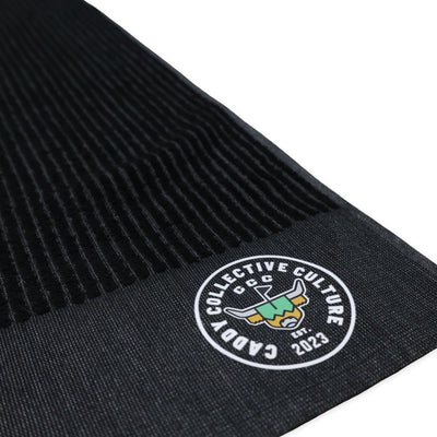 Close-up of printed Caddy Collective Culture logo on black golf towel