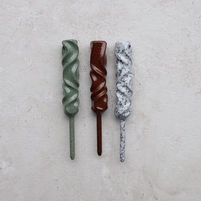 Dual-Twist single prong divot tools photographed on light stone surface highlighting handcrafted finishes