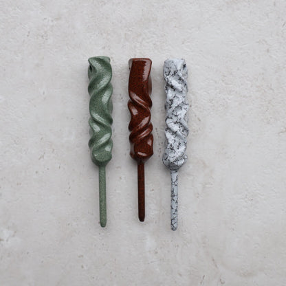 Dual-Twist single prong divot tools photographed on light stone surface highlighting handcrafted finishes