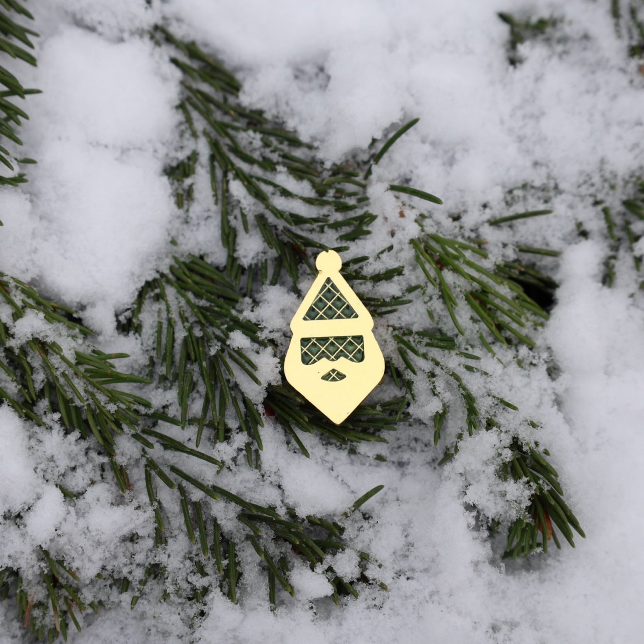Centered view of the Santa Silhouette ball marker on snow-covered pine needles.