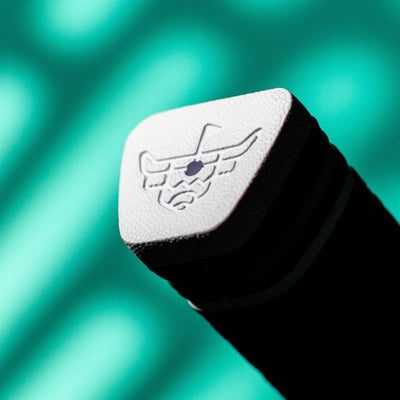 Macro photo of the white textured end cap on a black Garsen putter grip, showing an embossed caddy bull logo against a teal background.