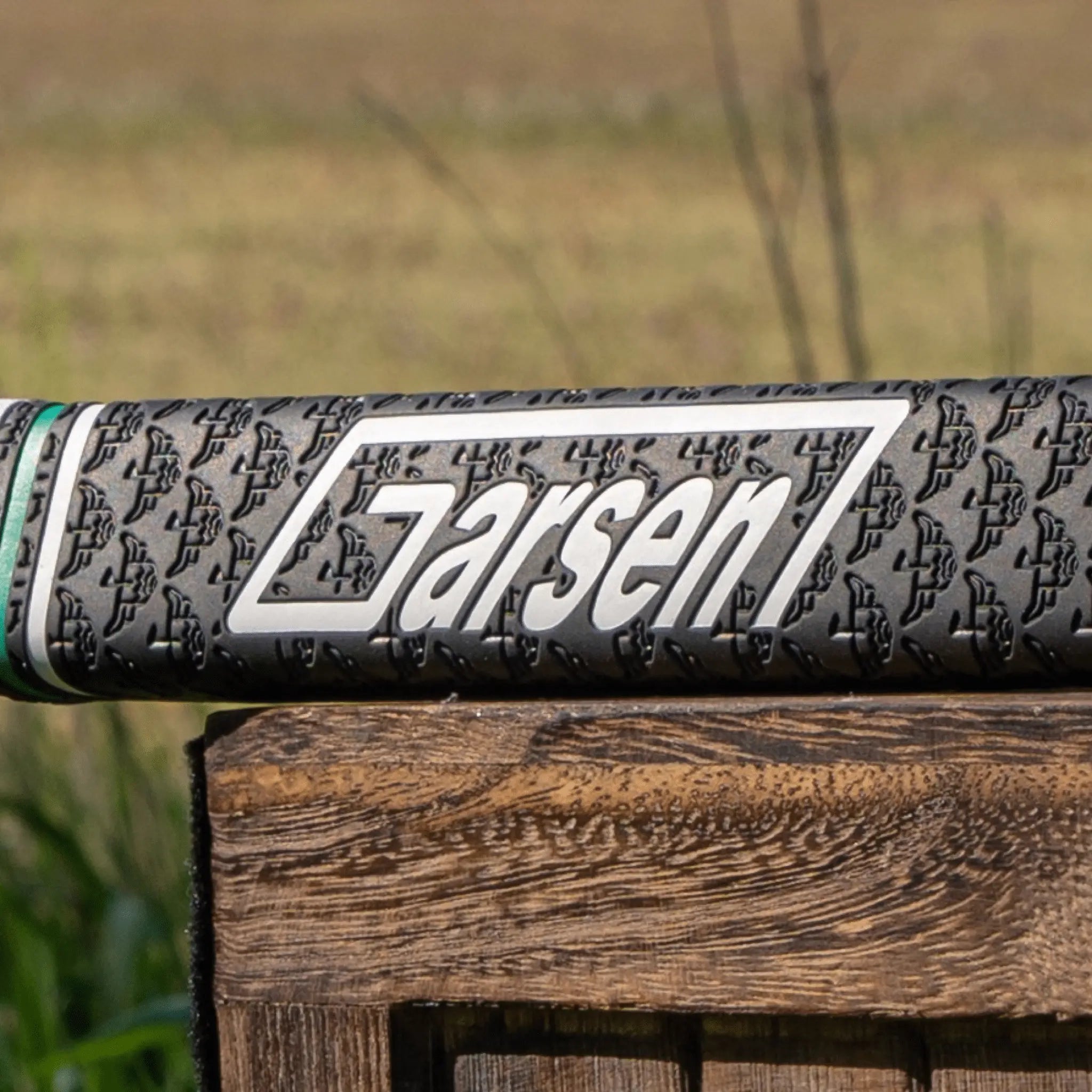 Side view of a black Garsen putter grip showing the large white Garsen logo over a repeating embossed pattern and green accent ring.