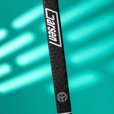 Angled view of a black Garsen QUAD Tour putter grip featuring the white Garsen logo, Caddy Collective Culture badge, and embossed texture on a teal background.