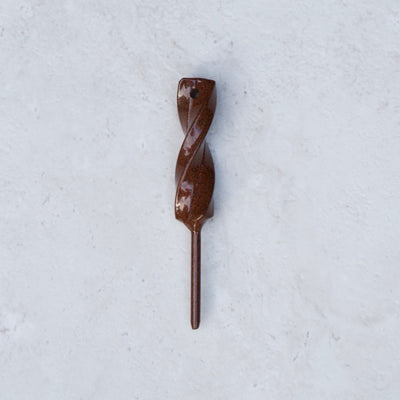 Rustic Hand Forged Twisted Divot Tool photographed on a textured stone background, showcasing the handcrafted twisted steel design.