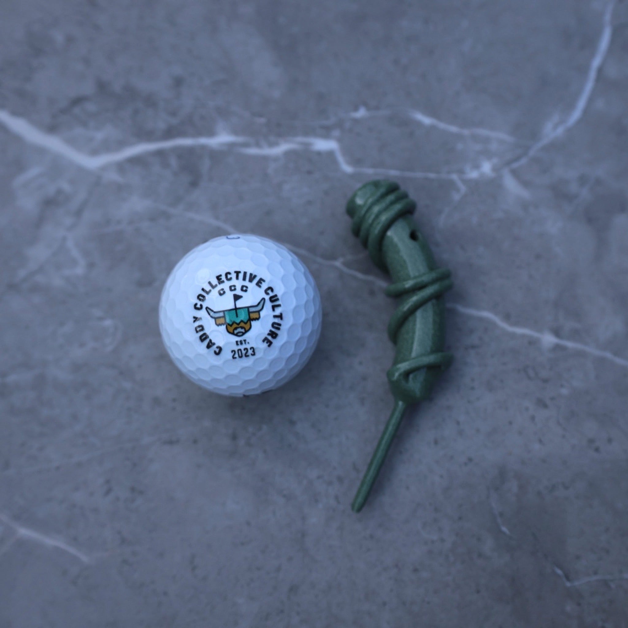 Hand Forged Wrapped Divot Tool in Sage Green finish displayed on a textured stone surface, showcasing the handcrafted wrapped steel design.