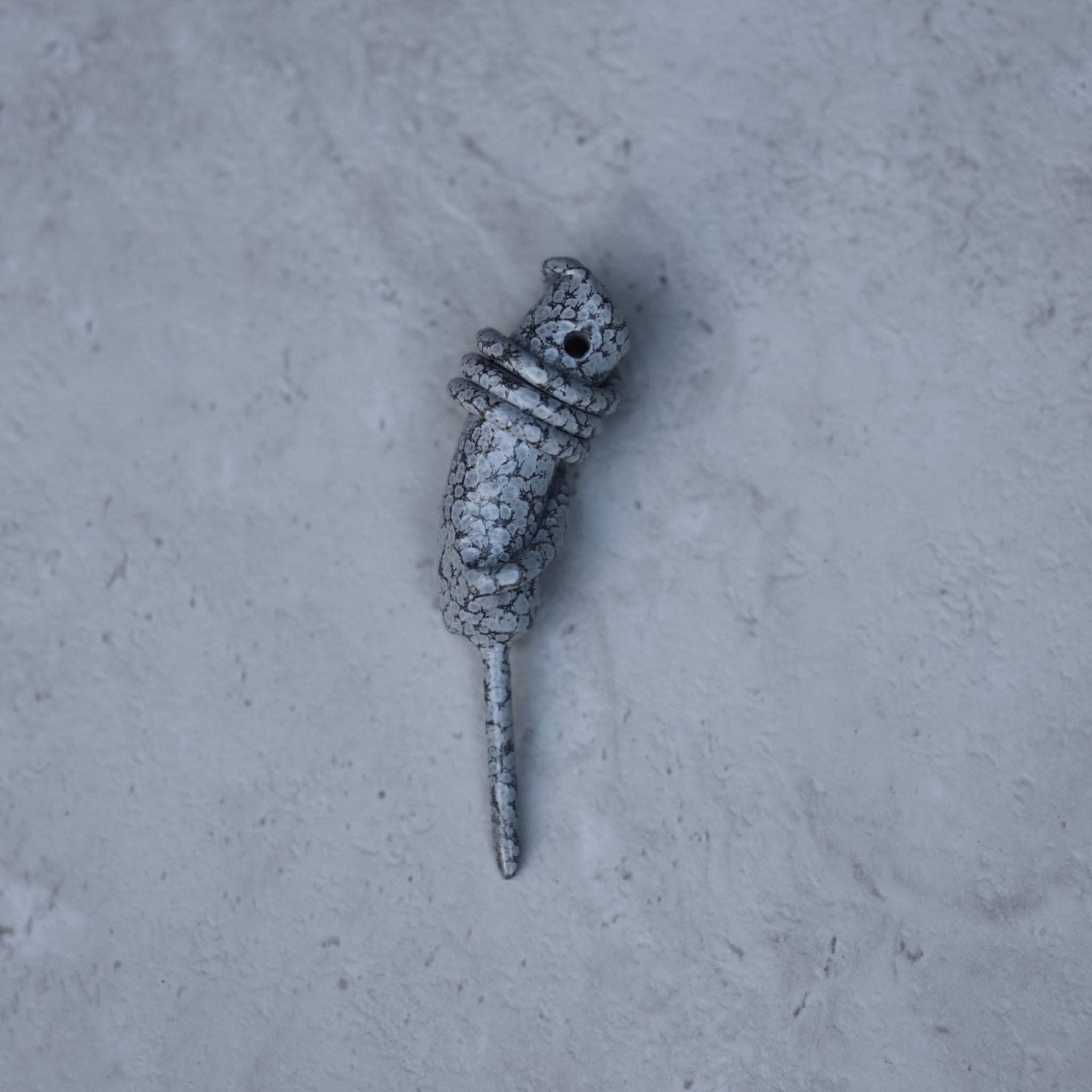 Hand Forged Wrapped Divot Tool in Stone White finish resting on a textured stone surface. Handcrafted single prong golf divot tool by Caddy Collective Culture.