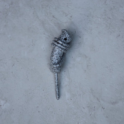 Hand Forged Wrapped Divot Tool in Stone White finish resting on a textured stone surface. Handcrafted single prong golf divot tool by Caddy Collective Culture.