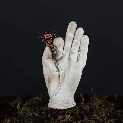 Looper After Dark divot tool displayed between lit candles in Halloween luxury setup