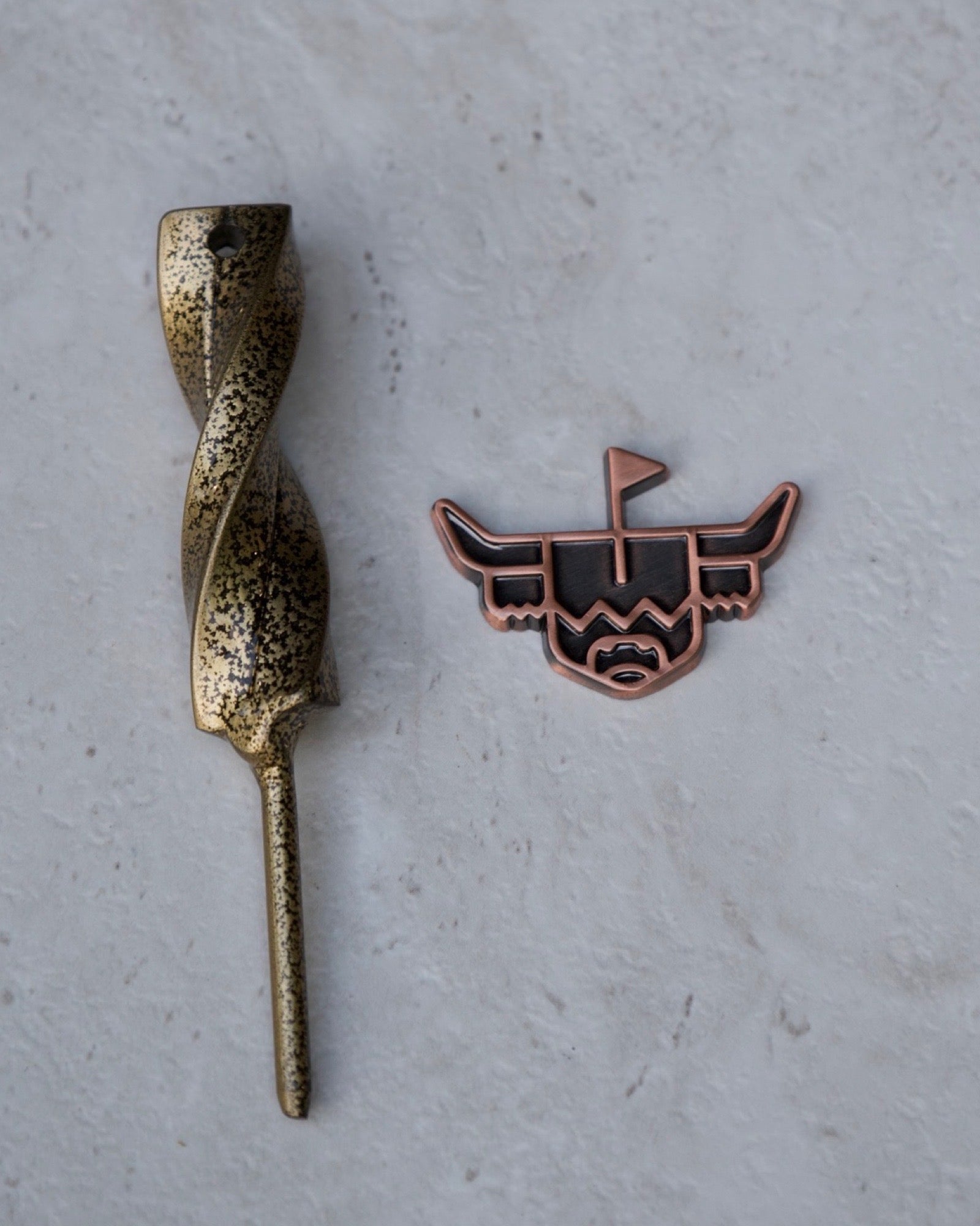 Looper Brass Ball Marker displayed beside a metal golf divot tool