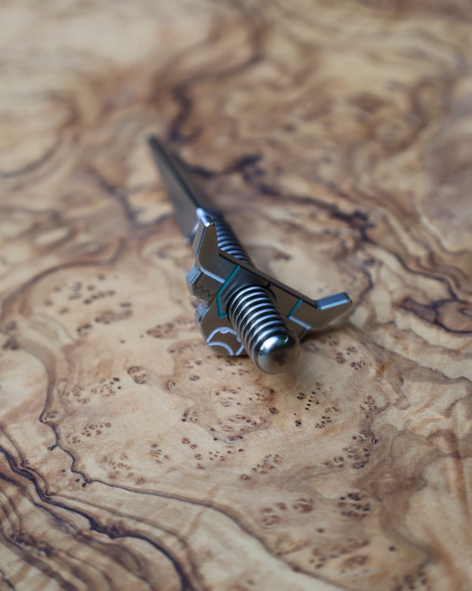 Looper Threaded Divot Tool displayed on olive wood highlighting handcrafted stainless steel construction.