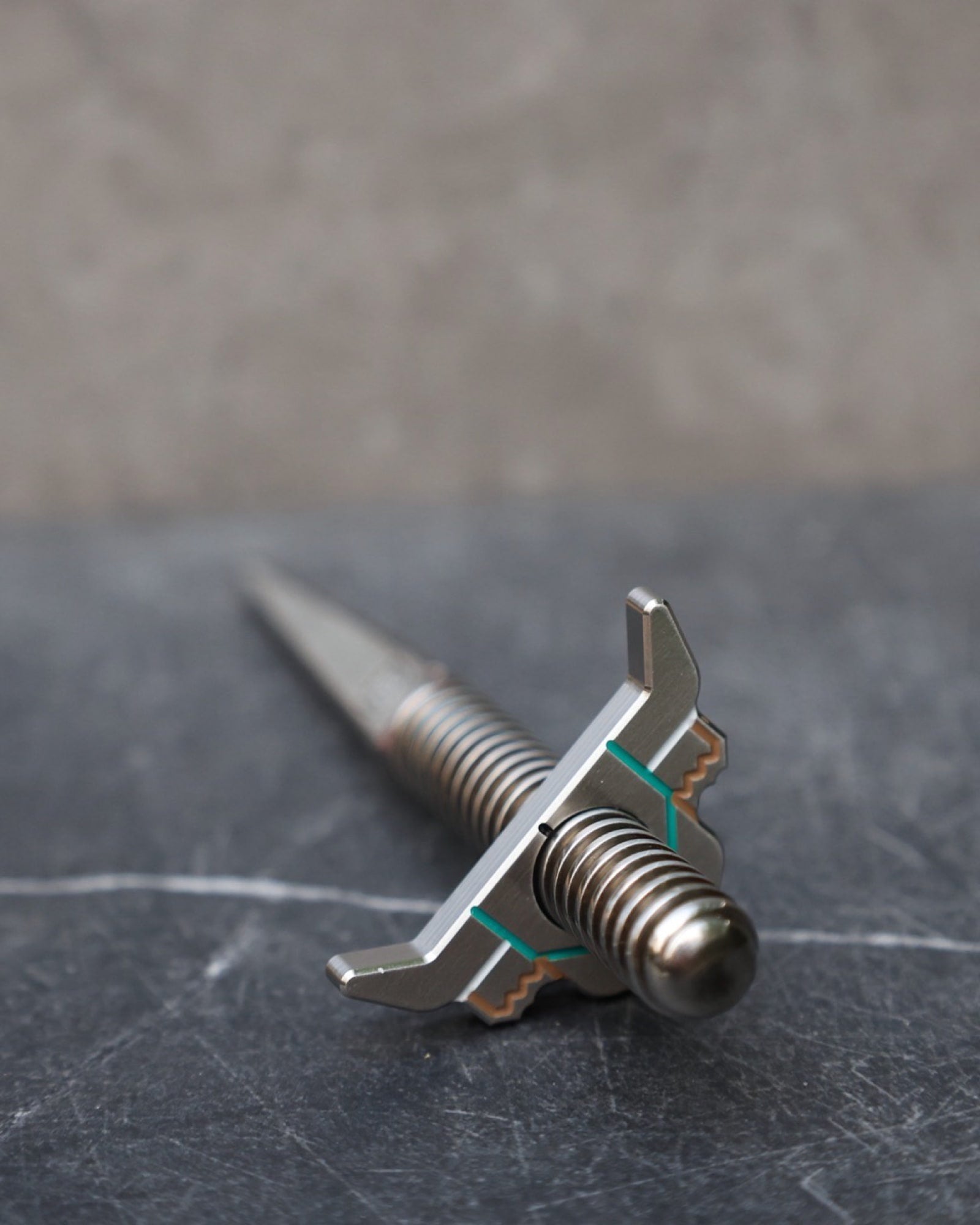 Looper Threaded Divot Tool handcrafted from stainless steel with threaded ball marker system on a slate surface.
