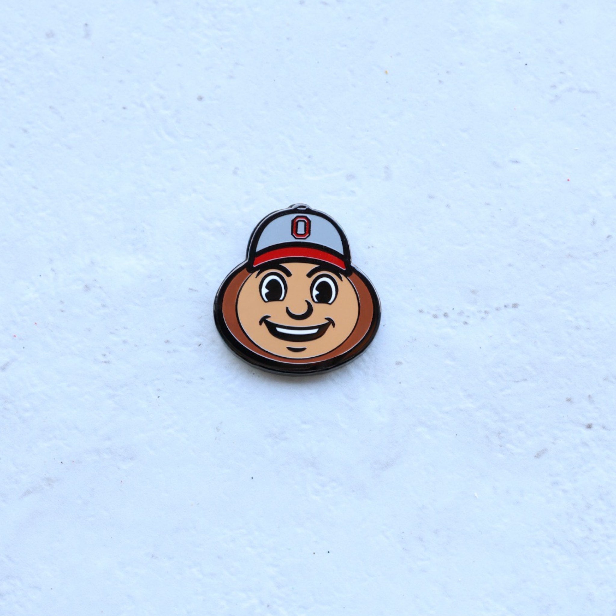 Ohio State Brutus Head golf ball marker photographed on textured surface