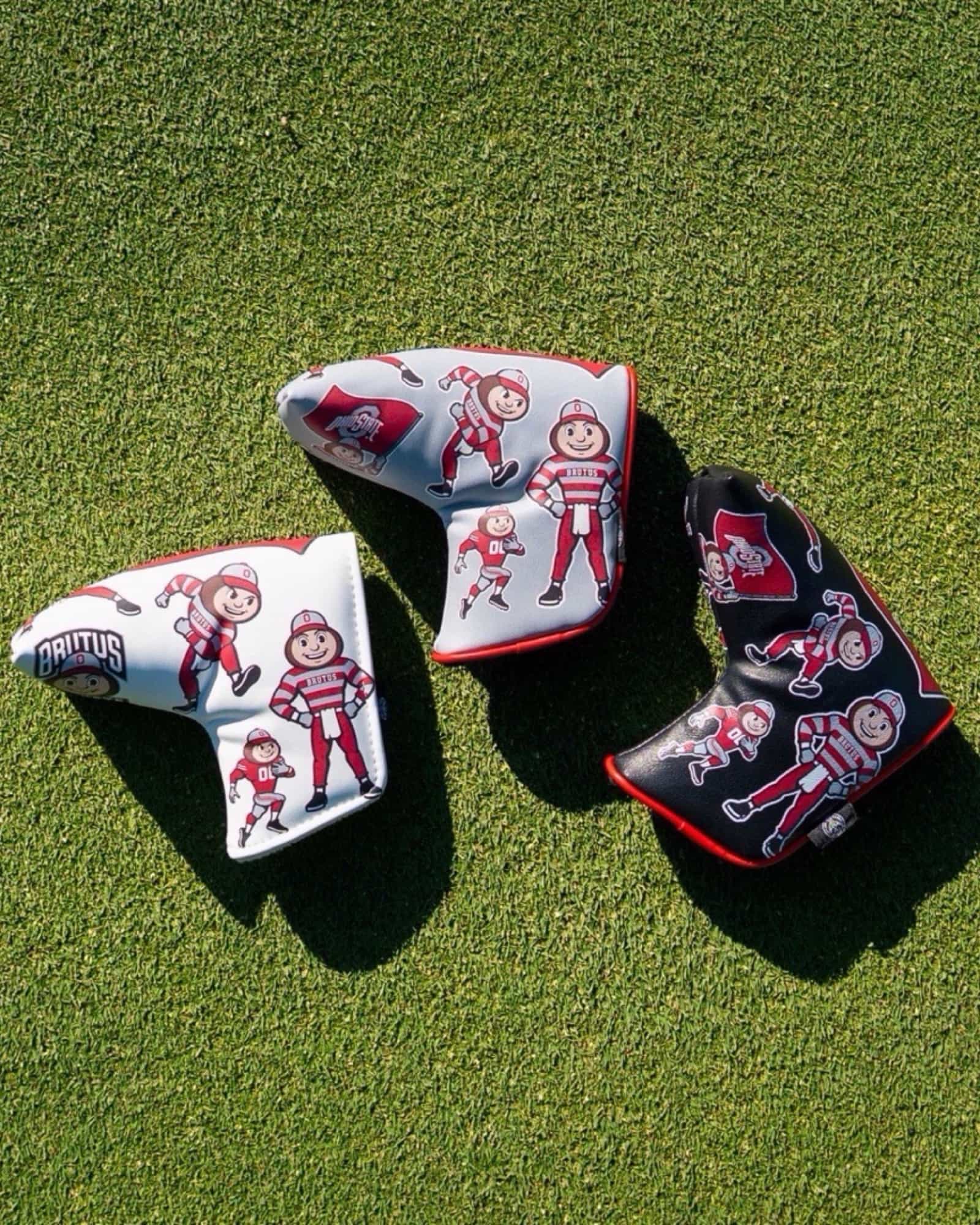 Ohio State Brutus Montage blade putter cover collection featuring white and black leather golf putter covers displayed on a putting green.