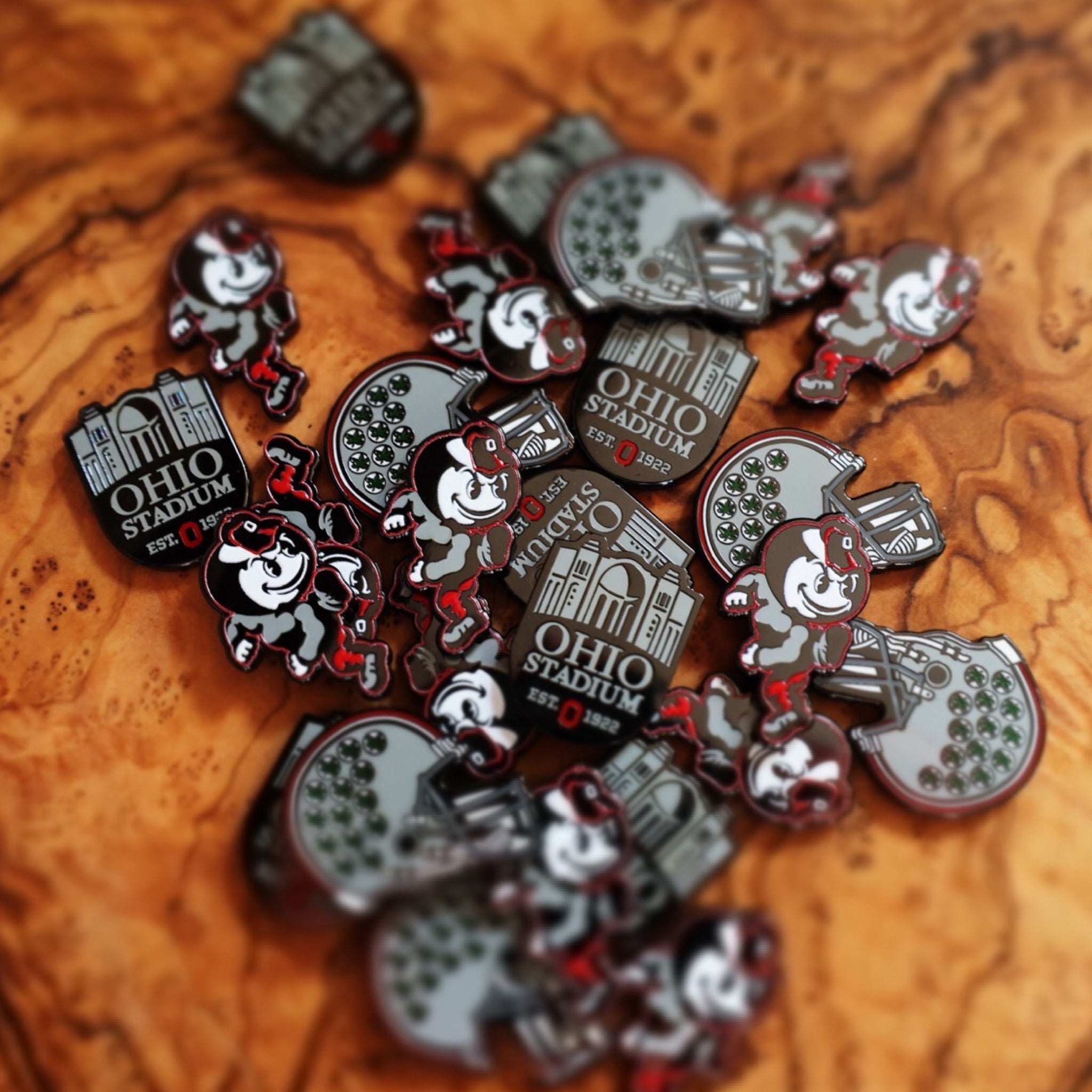Ohio State Heritage Brutus Ball Marker displayed among Buckeye Right Helmet and Horseshoe markers on natural wood surface