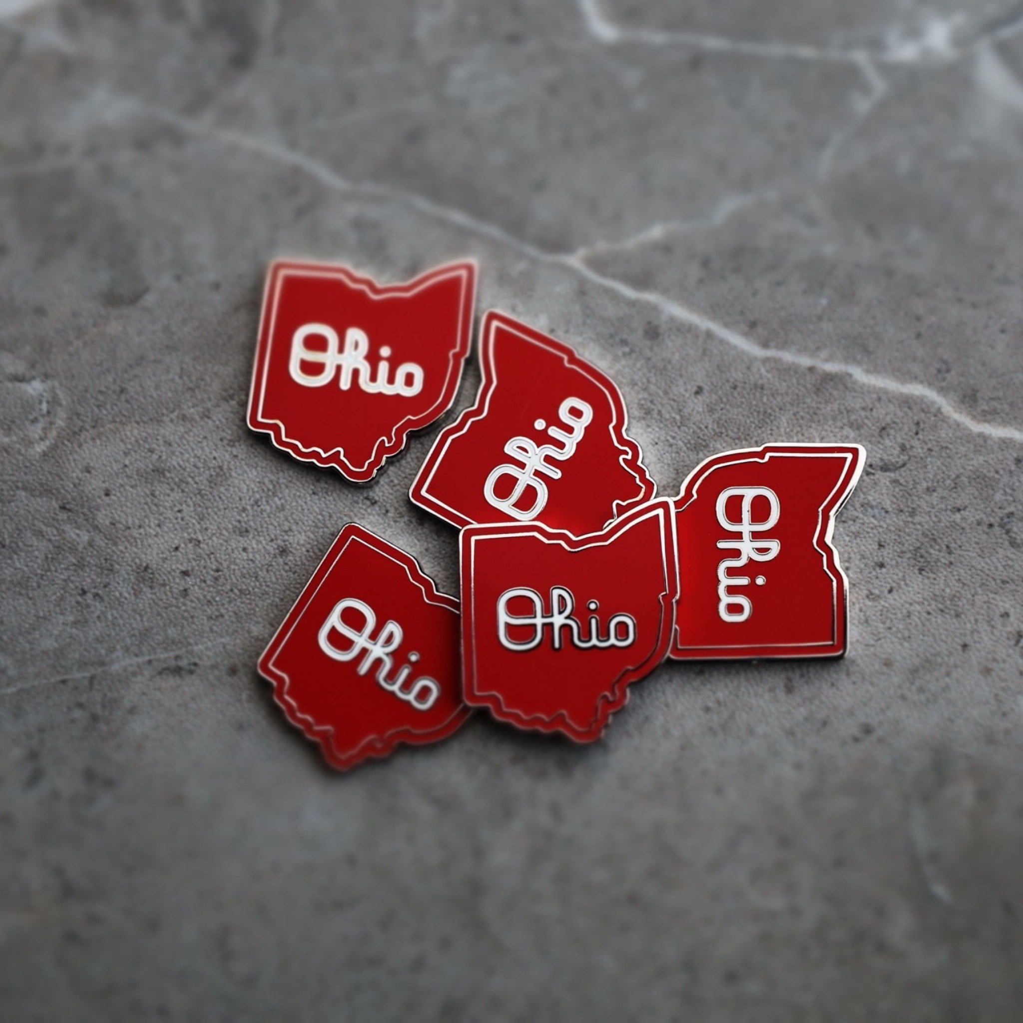 Multiple Script Ohio magnetic golf ball markers arranged on textured surface in red