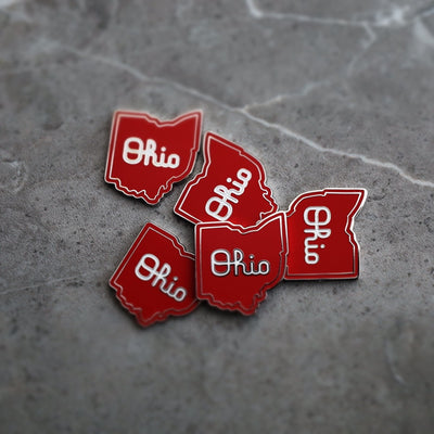 Multiple Script Ohio magnetic golf ball markers arranged on textured surface in red