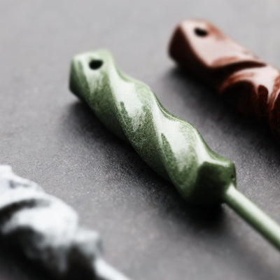 Angled detail view of Twisted Metal single prong divot tool in ithaca bronze finish showing sculpted hand-forged form